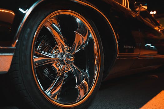 Detailed shot of a polished chrome car wheel reflecting urban lights.