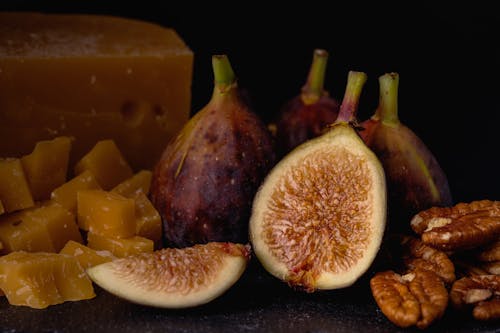 Close-Up Photo of a Halved Fig Beside Brown Walnuts