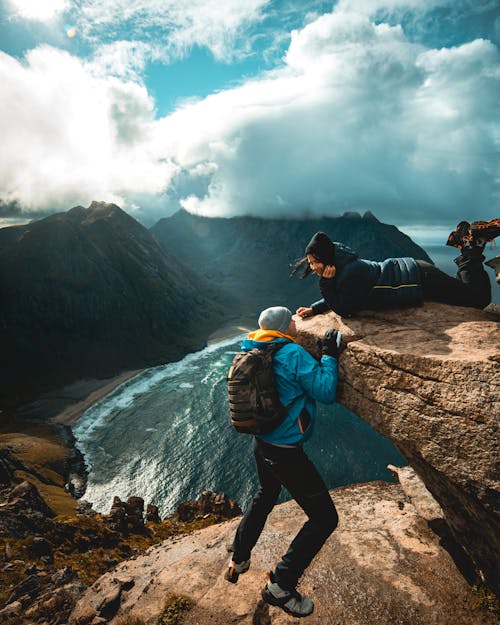 Man in Blue Jacket Hanging on a Cliff