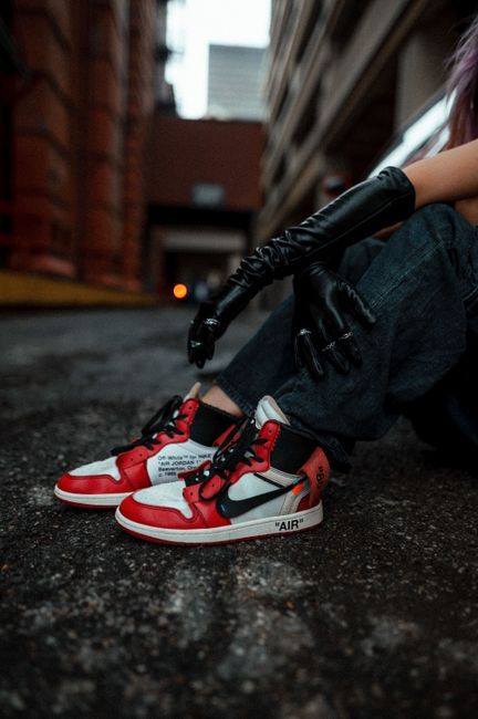 Chic urban photo of red sneakers and leather gloves on asphalt, showcasing street style.