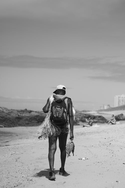 Monochrome Photo of a Fisherman Walking at the Beach