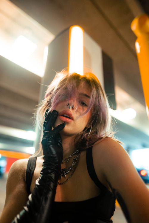Free Portrait of a stylish woman with pink hair and gloves in an urban setting, showcasing modern fashion indoors. Stock Photo