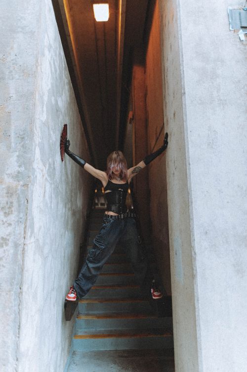 Free A stylish young woman poses dramatically in a narrow urban stairwell, exuding edgy fashion vibes. Stock Photo