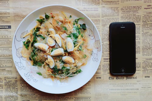 черный Iphone 5 рядом с тарелкой макаронного блюда