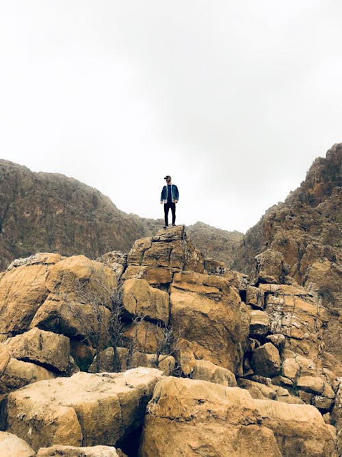 Man in Denim Jacket and Black Bottom Standing on Brown Concrete Stone