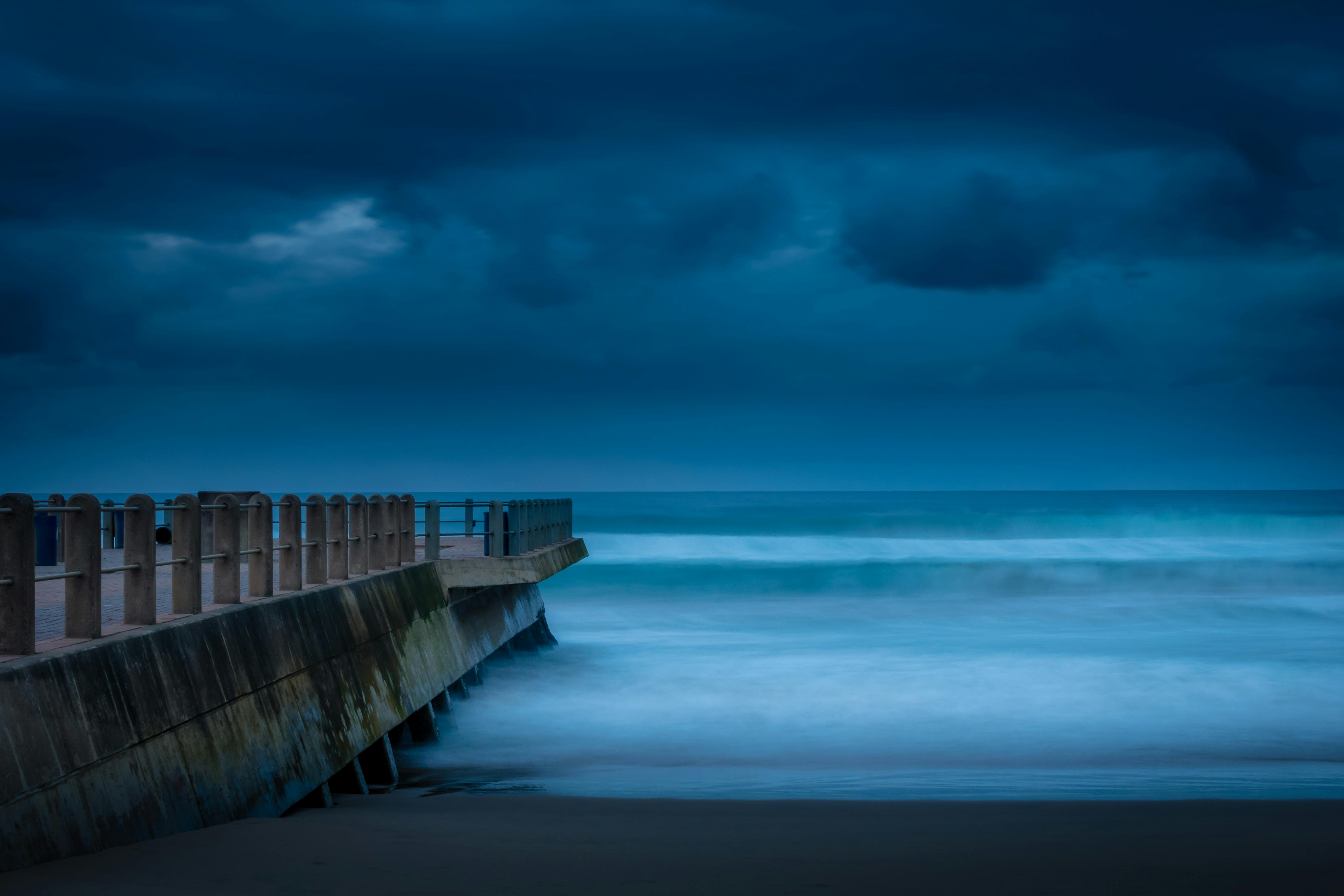 Serene view of a pier and ocean in Durban under a moody blue sky.