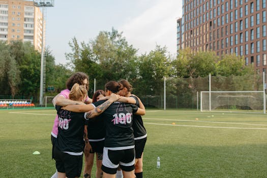 Women's football team huddles on a city field, emphasizing teamwork and sportsmanship.