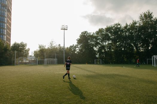 Young soccer player on a sunny field, practicing with a ball. Outdoor sports setting.