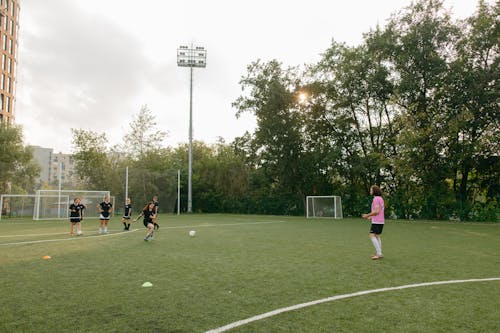 People Playing Soccer on Green Grass Field