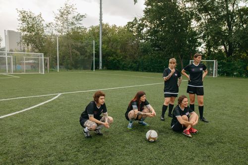 Free A group of women athletes in black soccer uniforms resting on an outdoor football field. Stock Photo