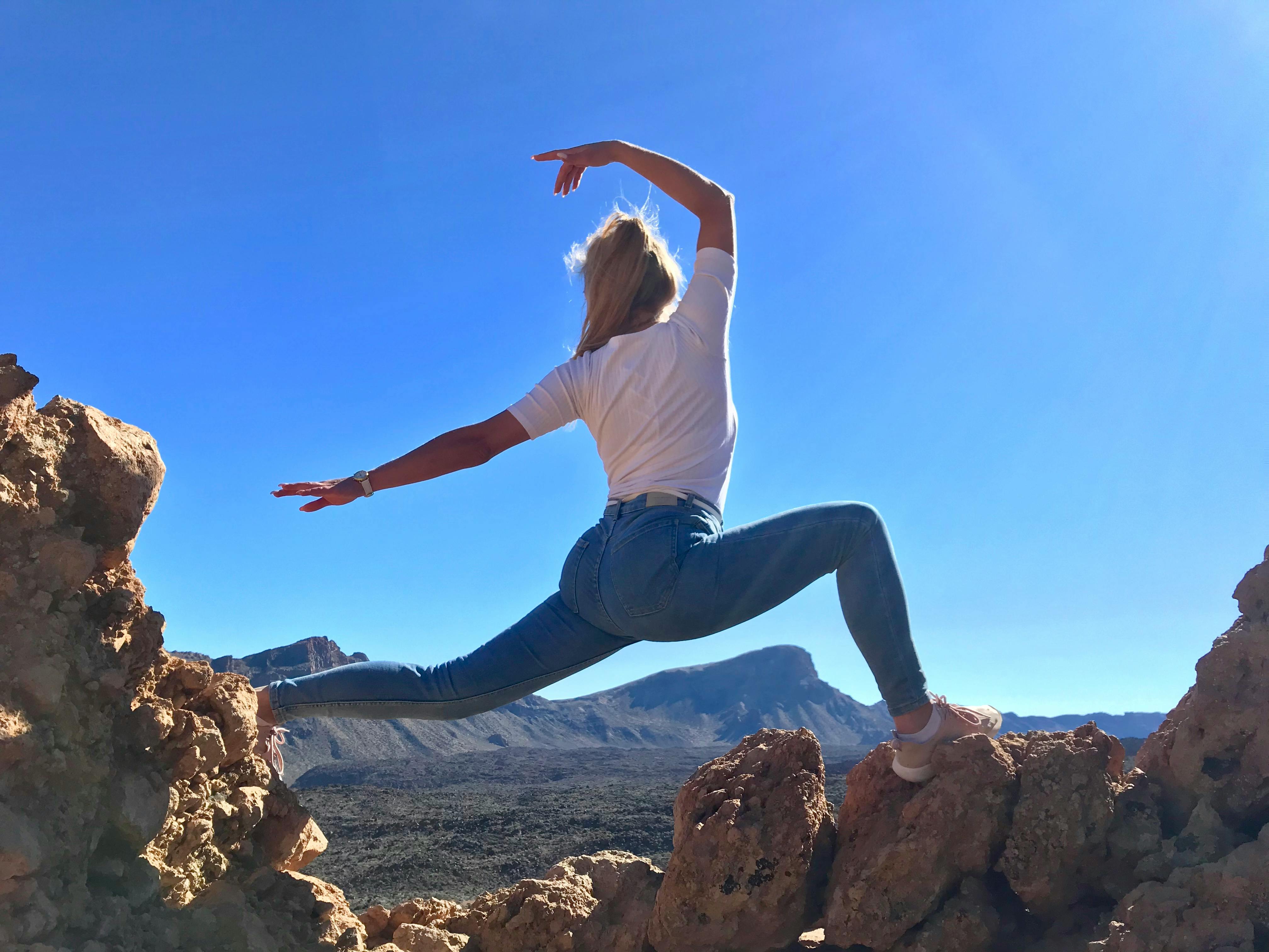 Woman in White T-shirt and Blue Jeans Doing Yoga on Rock Formation