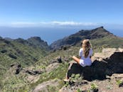 一个女人坐在岩石上，俯瞰着蓝天下的广阔山景