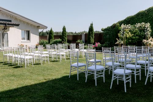 Free White chairs arranged in a garden setting for an outdoor wedding ceremony. Stock Photo
