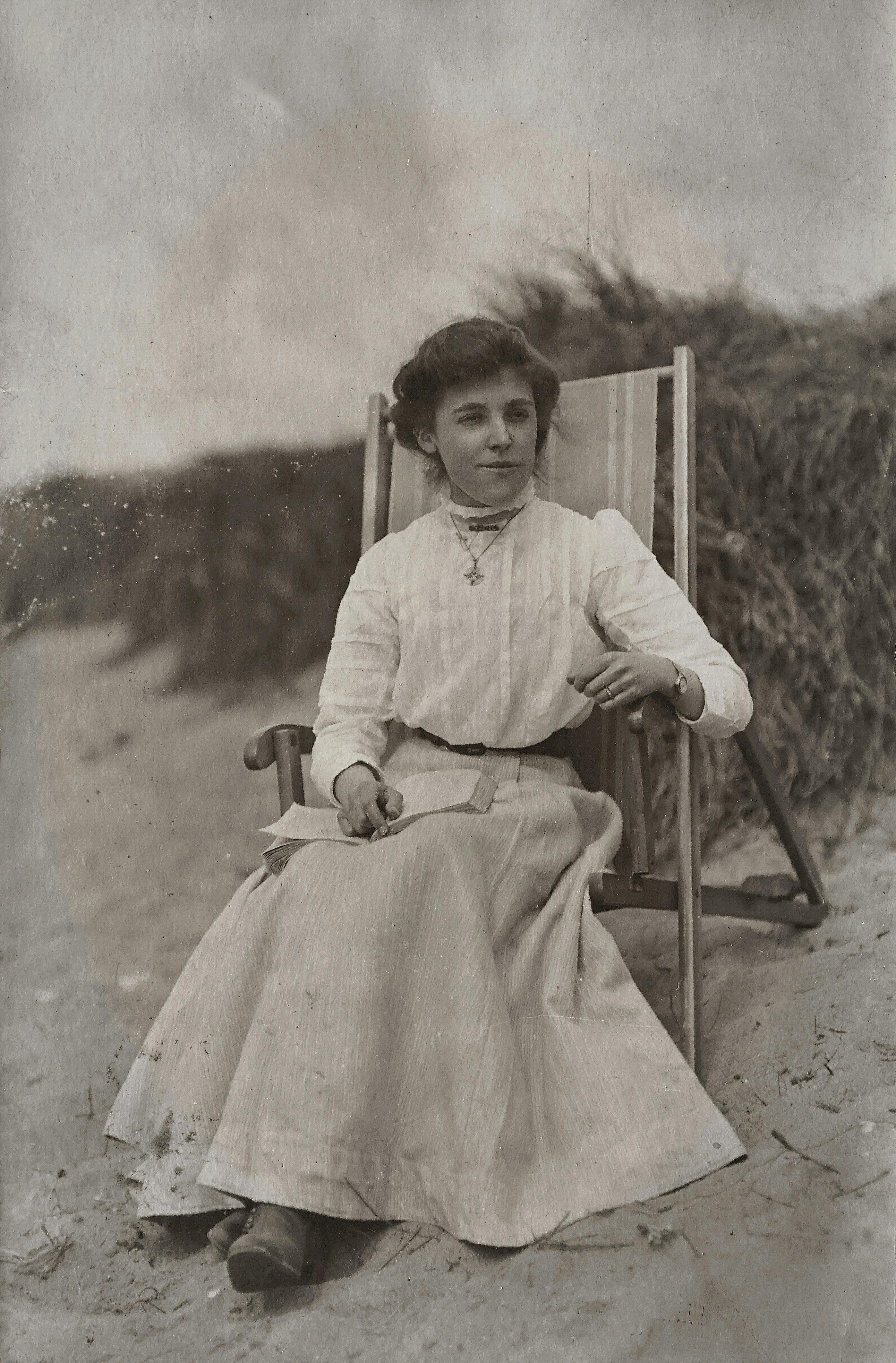 Grayscale vintage photo of a young woman sitting on a chair at the beach.