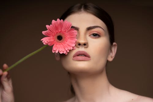 Free Woman Holding Pink Flower Against Her Eye Stock Photo
