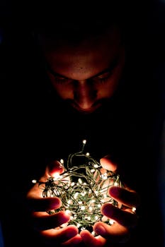 特写镜头中，一个男人手持发光的串灯，营造出神秘的氛围