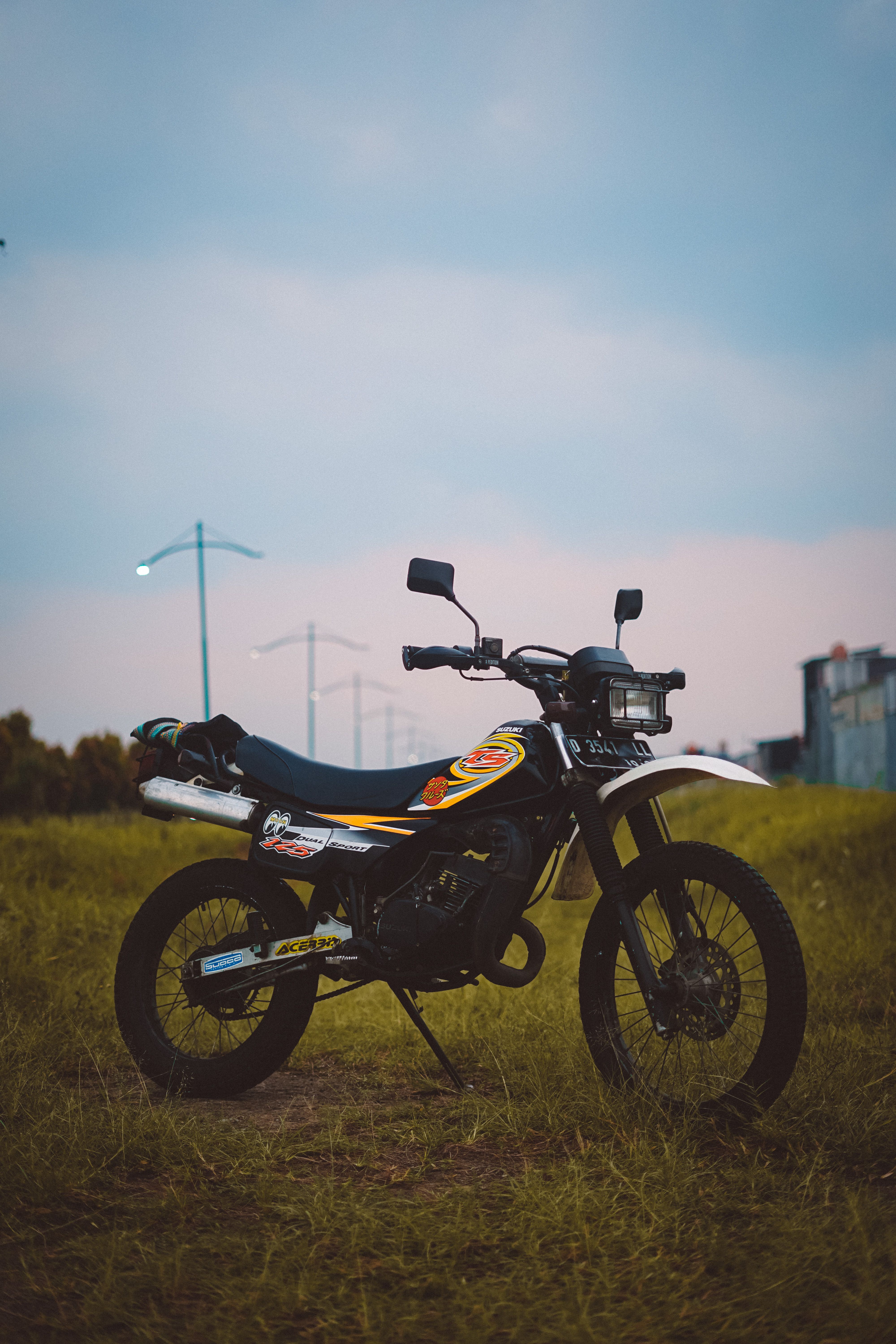 A sleek dirt bike parked on a grassy field under a dimming sky, capturing the essence of adventure.