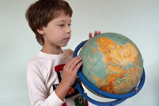 A young boy examines a desk globe indoors, fostering curiosity and learning about geography.
