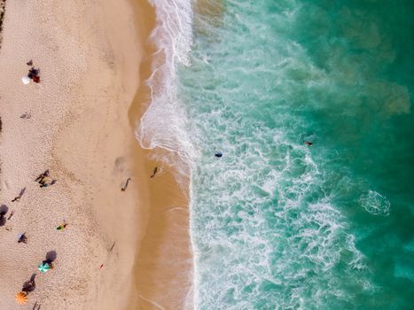 A stunning aerial shot of a beach in Rio de Janeiro with turquoise waves and sunbathers.