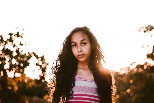 Portrait of a young girl with flowing hair, captured outdoors in golden sunlight.