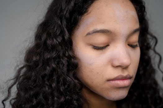 Portrait of a woman with curly hair and closed eyes, focusing on natural beauty and skincare.