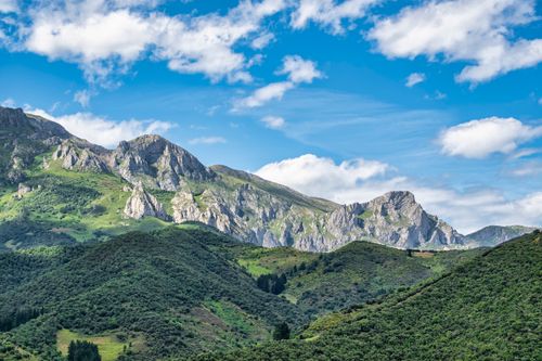Free Majestic mountain range with lush green hills under a clear blue sky. Stock Photo