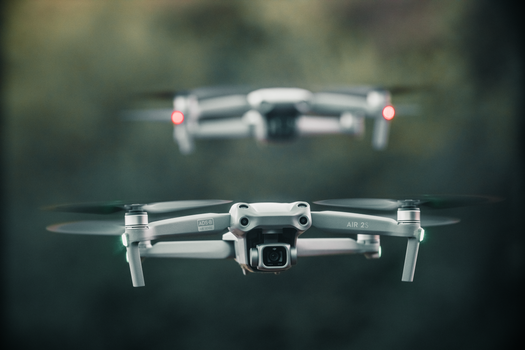 Close-up view of two drones in motion against a blurred background, outdoors.