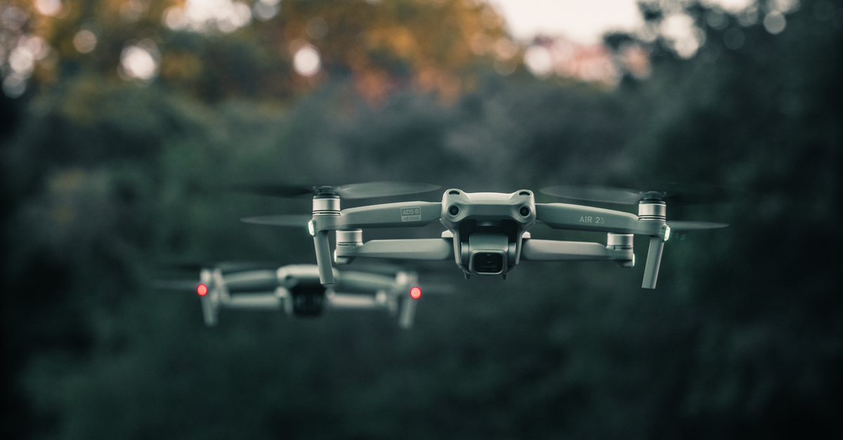A close-up of drones flying above a forest in Itchingfield, England, showcasing advanced technology.