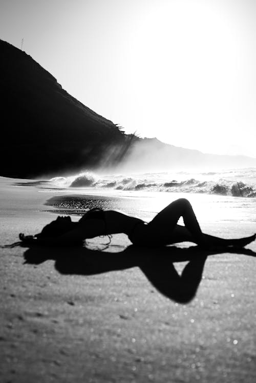 Woman in Black Bikini Lying on Beach Shore