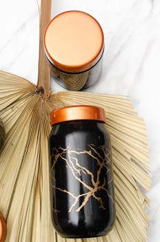 Elegant black jars with copper lids displayed on a natural palm leaf setting, perfect for modern decor.