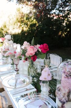 A beautifully decorated outdoor wedding table with elegant pink flowers and glassware.