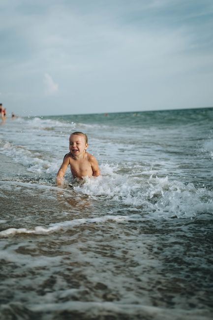 A young boy enjoys the summer waves at a picturesque beach, full of laughter and fun.