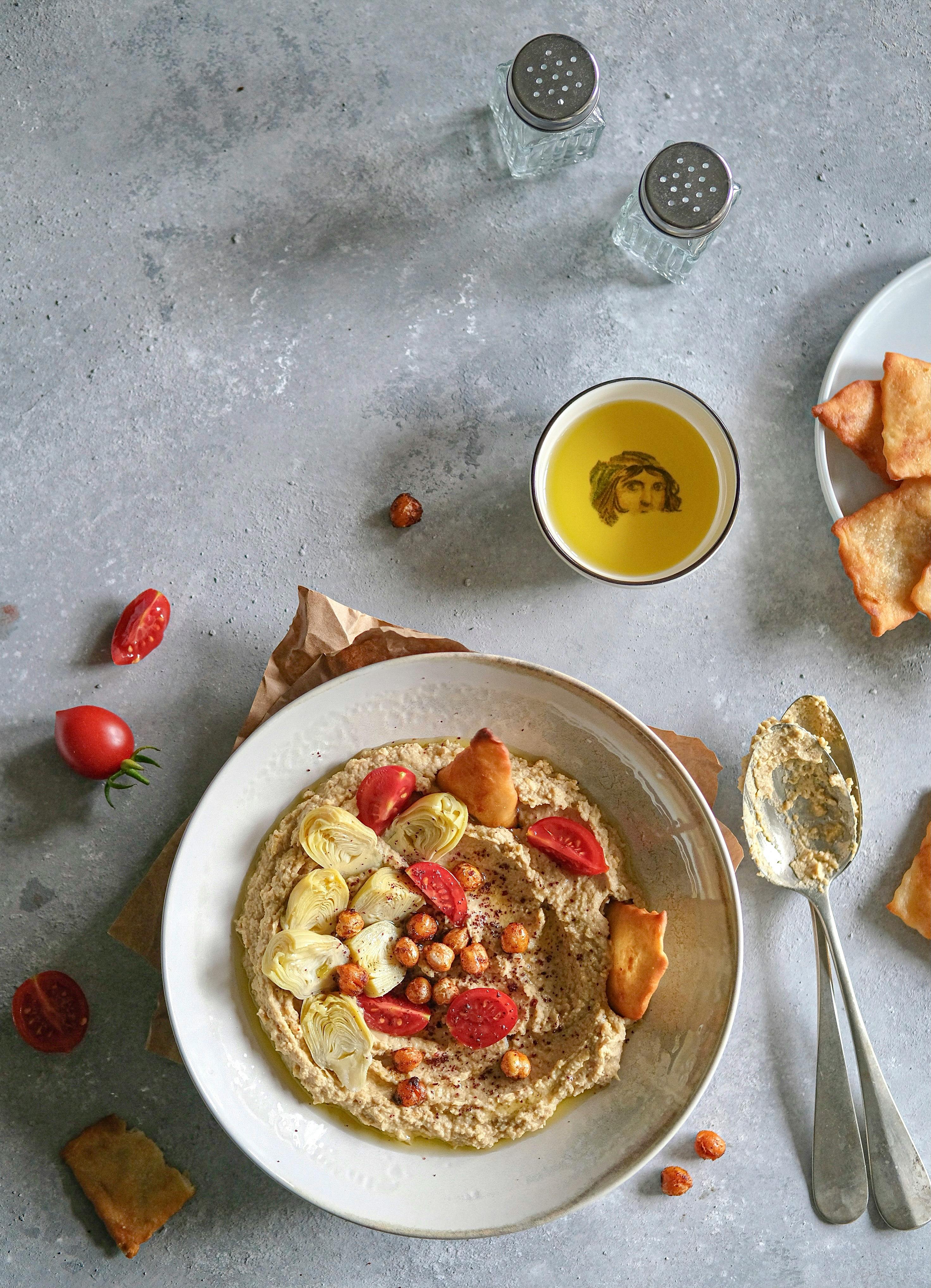 A delicious and nutritious bowl of hummus garnished with vegetables and served with crackers.