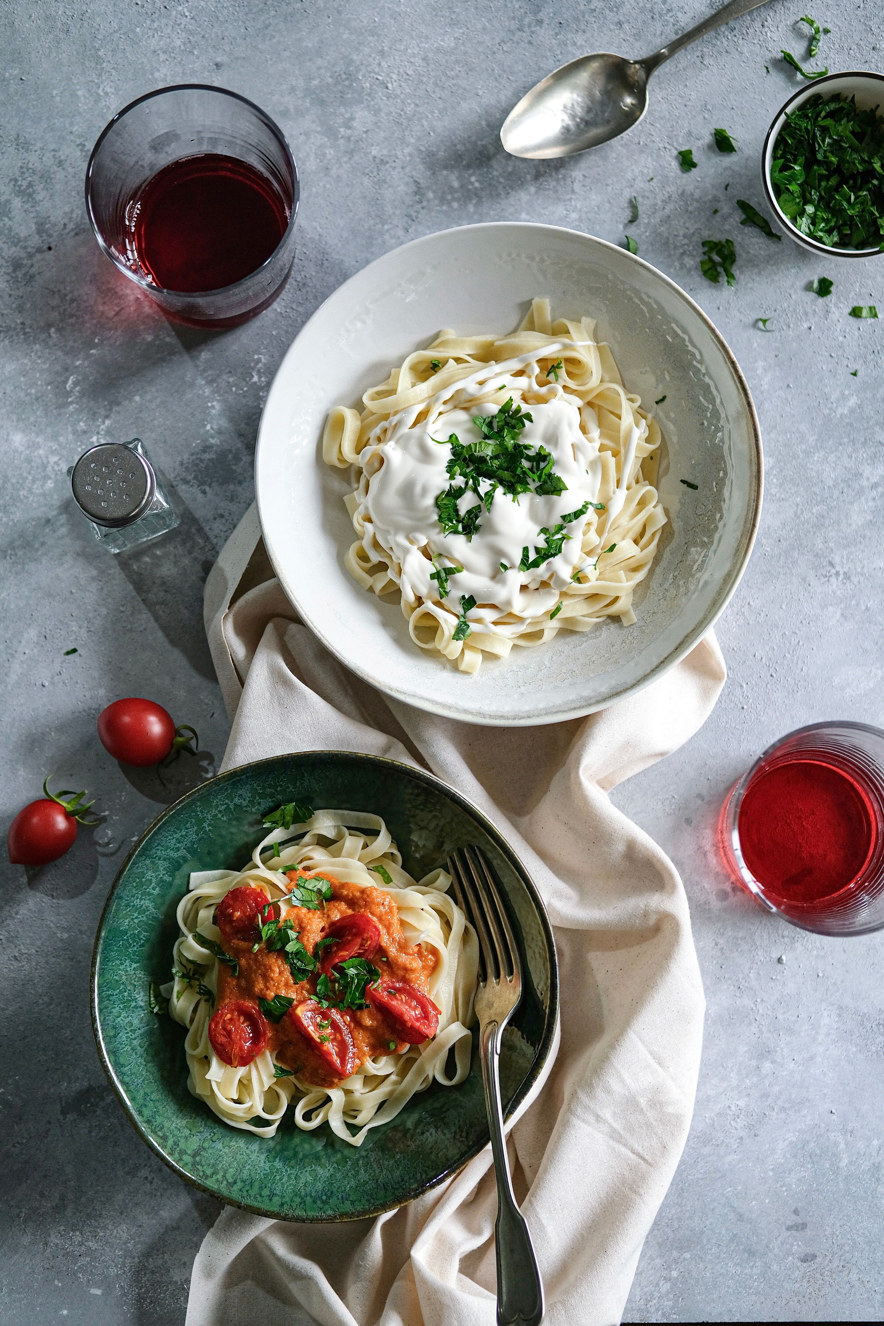 Two appetizing pasta dishes topped with fresh herbs and creamy sauce, served on a kitchen counter.