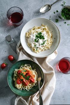 Two appetizing pasta dishes topped with fresh herbs and creamy sauce, served on a kitchen counter.