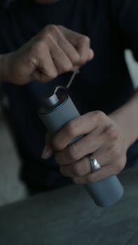 Detailed view of hands using a manual coffee grinder for food preparation.