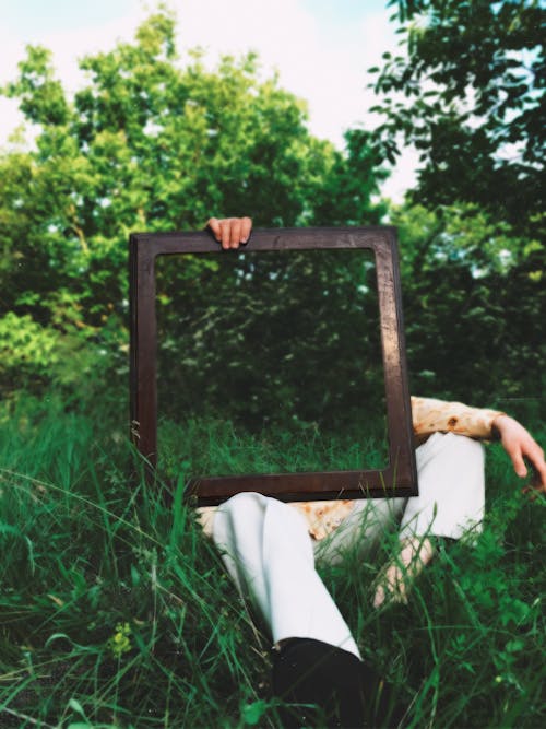 A Person Holding Brown Wooden Frame Mirror