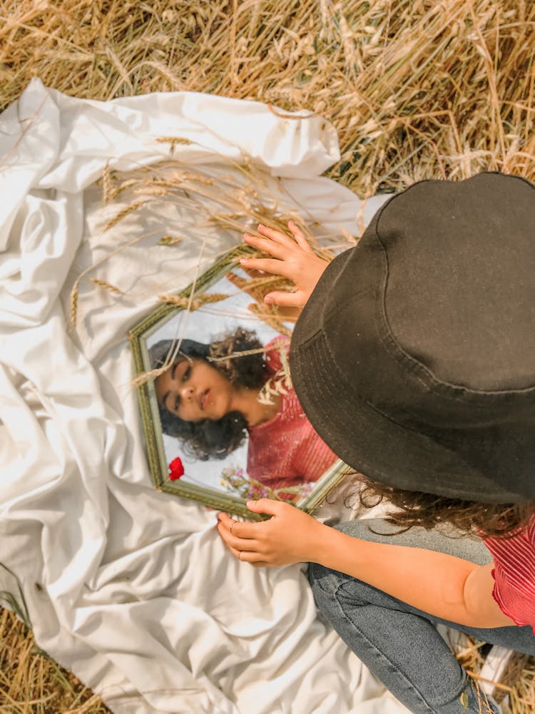 
A Woman Wearing A Hat Looking At A Mirror