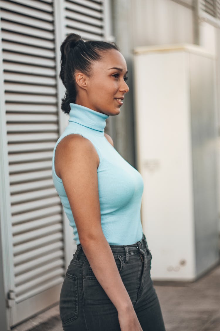 Woman Wearing A Turtleneck Shirt Standing Near A Wall