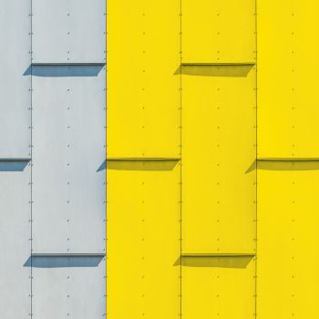 Vibrant minimalist facade featuring bold yellow and gray panels in Oslo, Norway—ideal for architectural backgrounds.