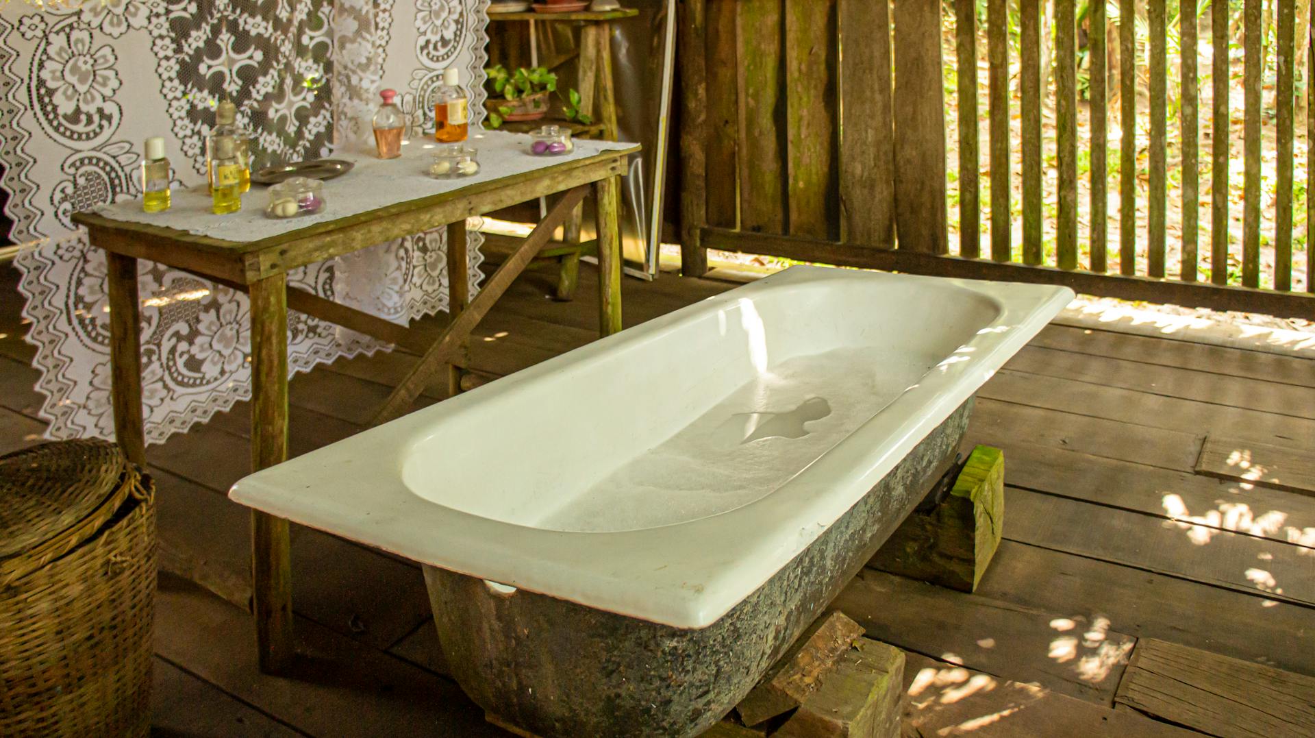 A rustic outdoor bathroom featuring a vintage bathtub and wooden decor in Brasil.