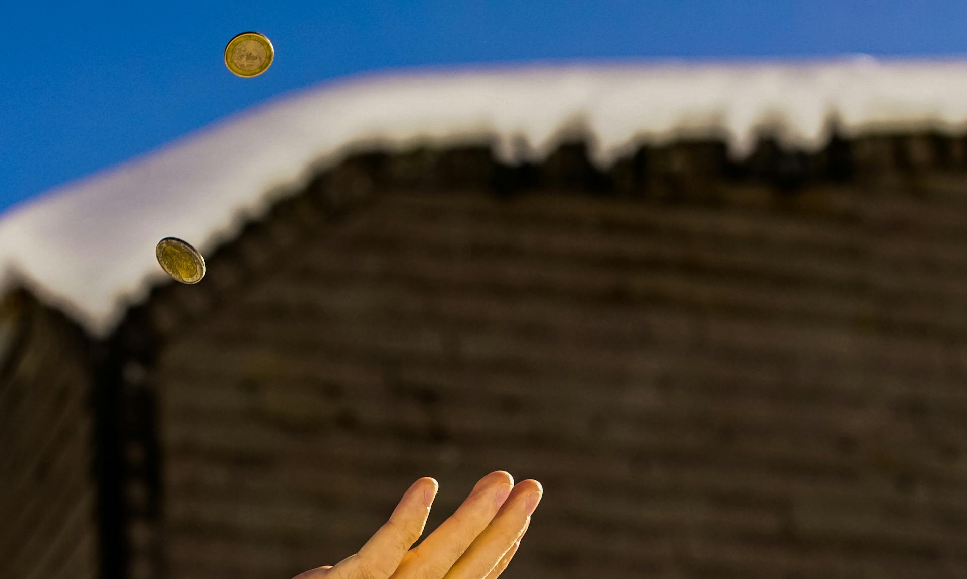 Shallow Focus Photography of Person Catching Two Gold-colored Coins