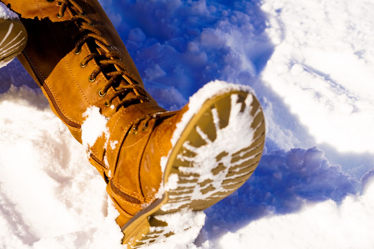 a tan winter boot in deep snow showing its tread