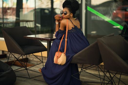 Stylish woman in sunglasses sitting outdoors at a café, exuding fashion and elegance.