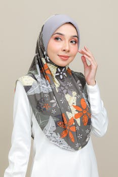 Portrait of a woman in a floral hijab posing gracefully against a neutral background.