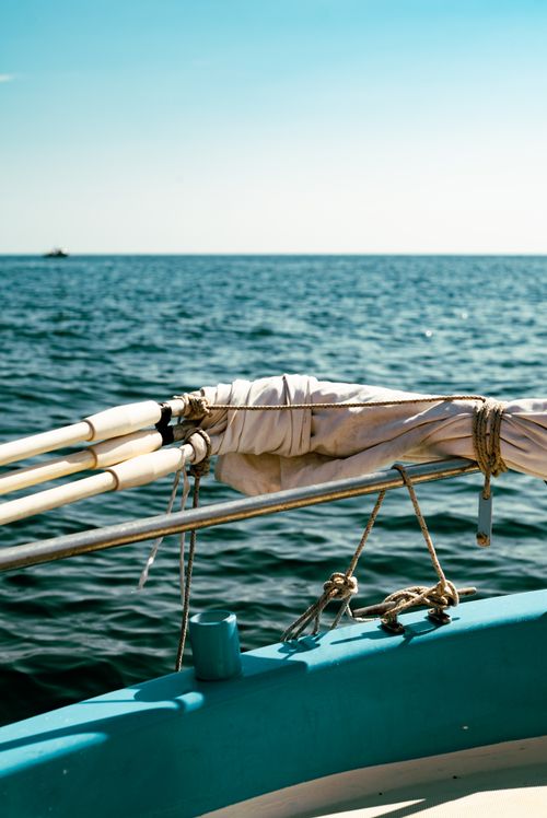 Free Close-up of a sailboat's bow on serene ocean waters under a blue sky. Stock Photo
