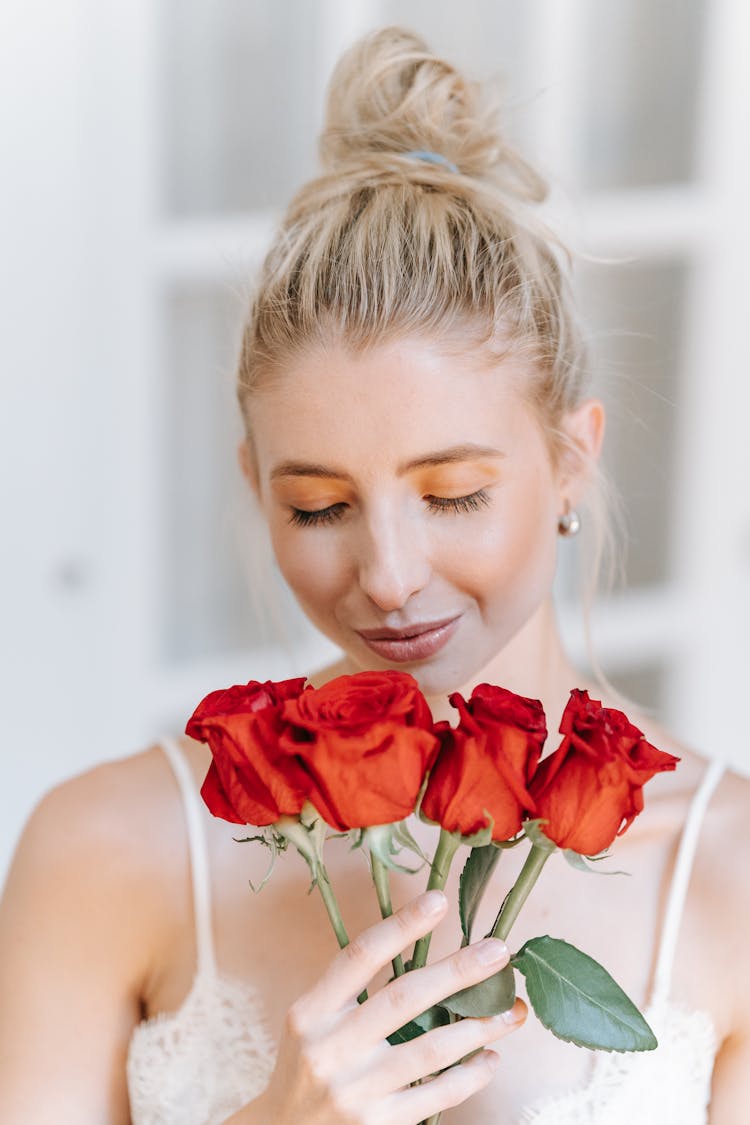 A Woman Smelling A Bunch Of Roses