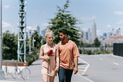 Free Young couple walking hand in hand outdoors with NYC skyline in the background. Stock Photo
