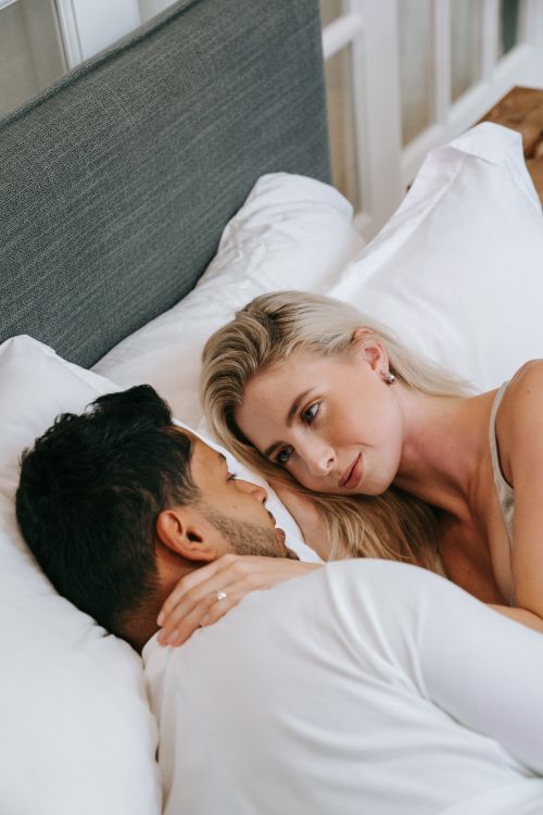 Free A loving couple embraces on a bed, creating a warm, intimate atmosphere. Stock Photo
