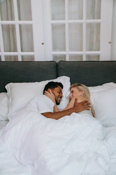 A loving couple smiling and embracing in a warm, cozy bedroom, symbolizing love and joy.
